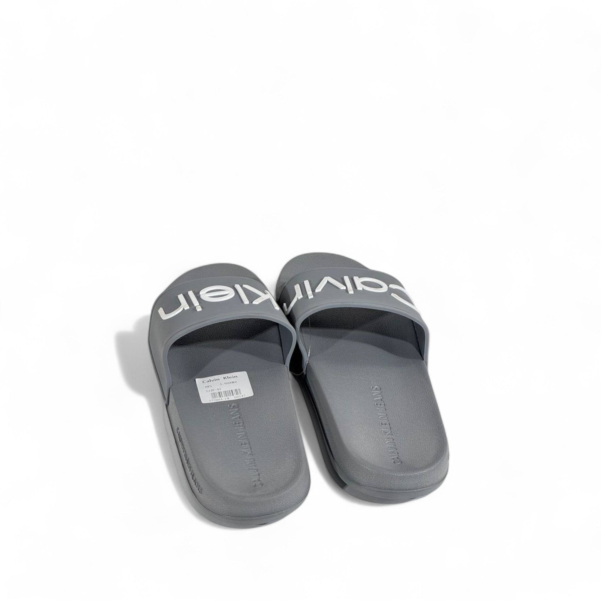 ⚪ Calvin Klein Grey Slides – Oversized White Logo Slippers
